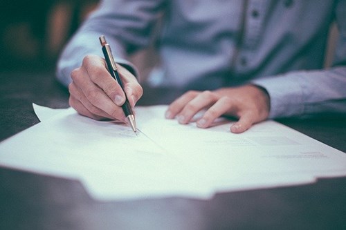 home warranties for landlord contract being signed by man with pen and blue shirt